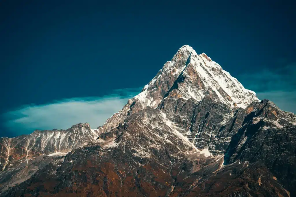 Majestätischer, schneebedeckter Berggipfel vor einem tiefblauen Himmel mit Wolken